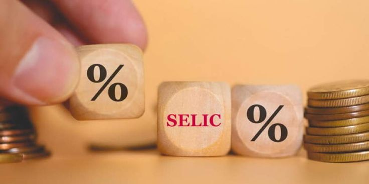 Cubos com símbolos de porcentagem e a palavra Selic entre moedas, representando o investimento em Tesouro Selic e sua relação com os juros.